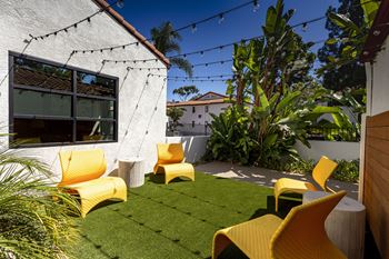 A backyard with yellow chairs and a green lawn